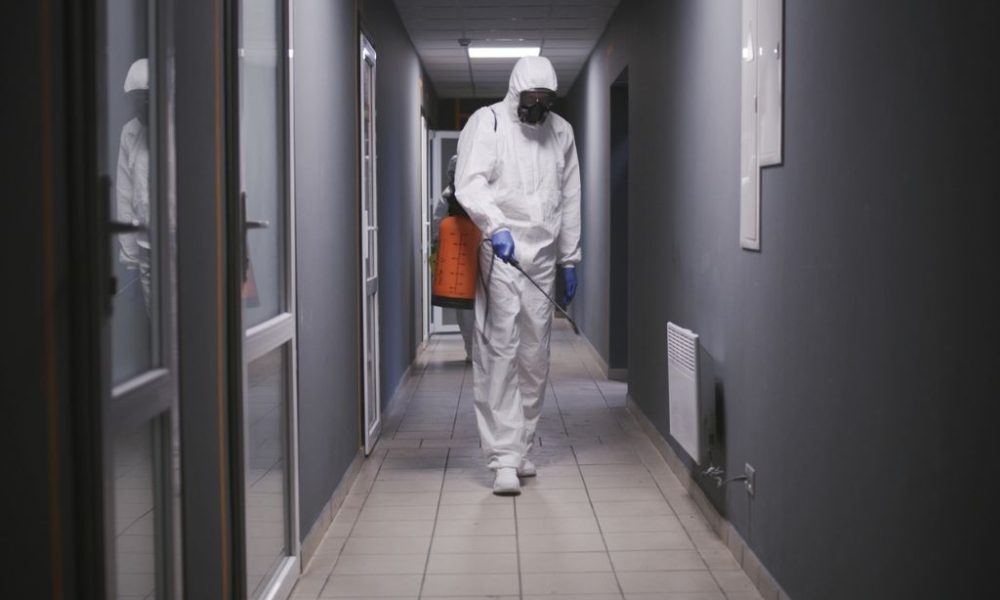 Man in a hazmat suit disinfecting a building in Orlando, FL